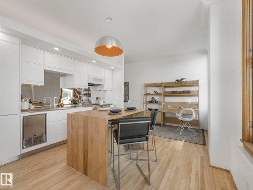The kitchen features light wood flooring, white cabinetry, a wooden island, and an integrated stainless steel appliance - 807 10134 100 Street, Edmonton, AB - Indoor Photo Showing Kitchen