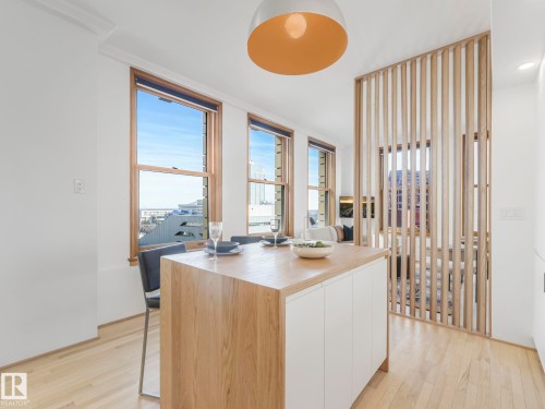Contemporary kitchen island with a light wood countertop, white cabinetry, and seating for two - 807 10134 100 Street, Edmonton, AB - Indoor