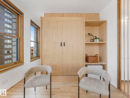 This room features light-toned wood flooring and window frames, built-in wooden cabinetry, and open shelving - 807 10134 100 Street, Edmonton, AB - Indoor Photo Showing Other Room
