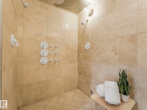 This shower features light-colored tiled walls and floor, two shower heads, and an additional set of three body sprayers - 807 10134 100 Street, Edmonton, AB - Indoor Photo Showing Bathroom