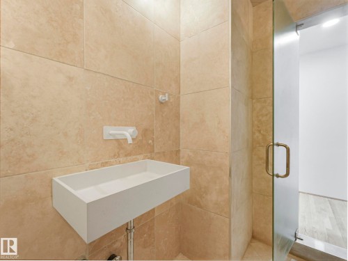 Bathroom featuring a wall-mounted sink, a wall-mounted faucet, and a glass door - 807 10134 100 Street, Edmonton, AB - Indoor Photo Showing Bathroom