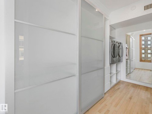 The property features hardwood flooring, a laundry area with a washer and dryer, and built-in shelving - 807 10134 100 Street, Edmonton, AB - Indoor