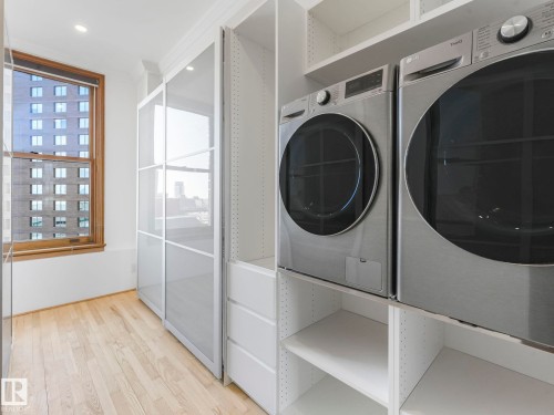 Room featuring light hardwood floors, built-in shelving, and a window with wood trim - 807 10134 100 Street, Edmonton, AB - Indoor Photo Showing Laundry Room