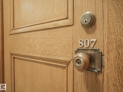 The property entrance features a paneled wooden door with a brass door handle and deadbolt - 807 10134 100 Street, Edmonton, AB - Indoor Photo Showing Laundry Room