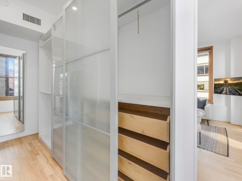 Walk-in closet with built-in shelving, frosted glass sliding doors, and light wood flooring - 807 10134 100 Street, Edmonton, AB - Indoor