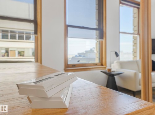 Room featuring large windows with wooden frames and roller shades, offering views of the surrounding urban landscape - 807 10134 100 Street, Edmonton, AB - Indoor