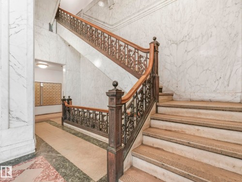 The property features a grand staircase with ornate metal railings and a wooden handrail - 807 10134 100 Street, Edmonton, AB - Indoor Photo Showing Other Room