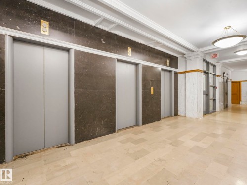 The property features a hallway with light-colored tile flooring and dark stone walls - 807 10134 100 Street, Edmonton, AB - Indoor Photo Showing Other Room