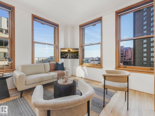 Living area featuring light wood flooring, white walls, and wood-framed windows providing natural light and city views - 807 10134 100 Street, Edmonton, AB - Indoor Photo Showing Living Room