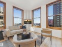 Living area featuring light wood flooring, white walls, and wood-framed windows providing natural light and city views - 807 10134 100 Street, Edmonton, AB  - Indoor Photo Showing Living Room 