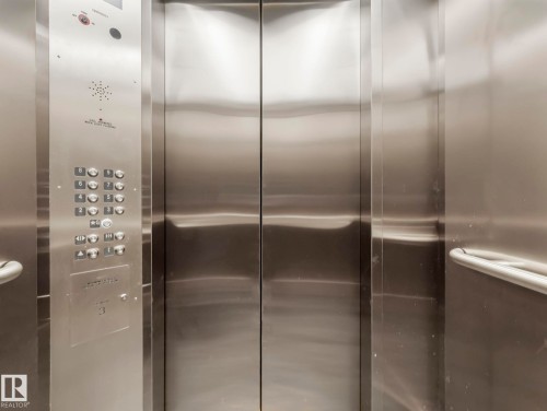 The property features an elevator with brushed metal interior walls, a control panel with numerous buttons, and a metal handrail - 807 10134 100 Street, Edmonton, AB - Indoor