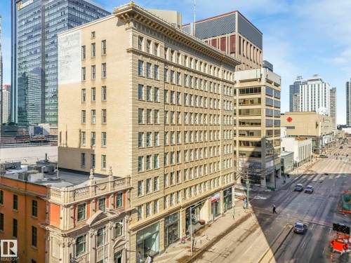 The property is a multi-story building featuring a light-colored facade with numerous windows - 807 10134 100 Street, Edmonton, AB - Outdoor With Facade