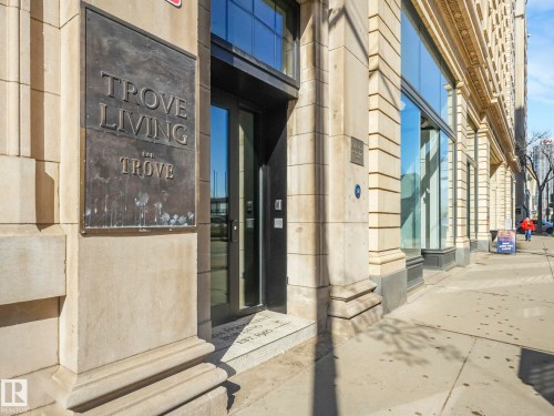The property features a distinguished stone facade with large storefront windows and a glass entrance door - 807 10134 100 Street, Edmonton, AB - Outdoor