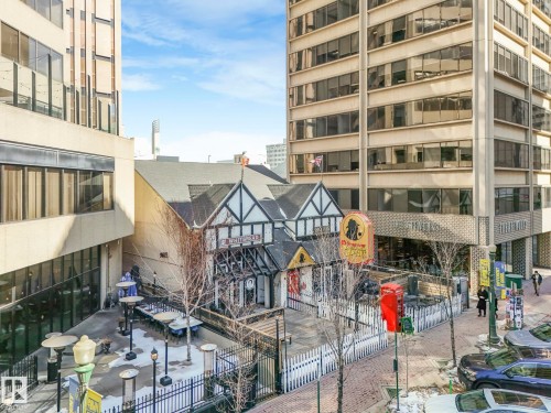 The property features a Tudor style building with a distinctive facade, surrounded by an outdoor patio area - 807 10134 100 Street, Edmonton, AB - 