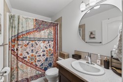 Bathroom vanity with an integrated oval sink and chrome faucet, complemented by a large circular mirror and overhead lighting - 