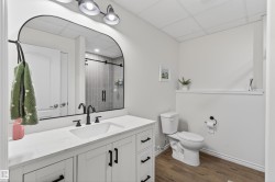 Bathroom featuring a white vanity with a rectangular undermount sink, matte black faucet, and a large arched mirror - 
