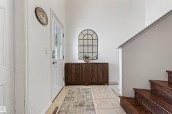 Entryway featuring a white paneled door with glass inserts, tile flooring, and a rich wood-finish staircase - 