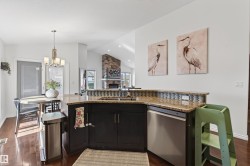 Open-concept kitchen featuring dark wood cabinetry, granite countertops, and a stainless steel dishwasher - 
