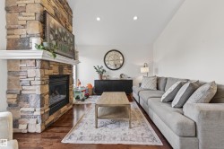 Stacked stone fireplace with a white mantelpiece, wood-finish flooring, and recessed lighting - 