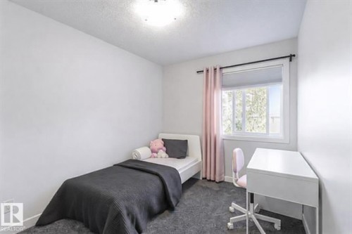 This room features light-colored walls and a window with blinds and drapes, allowing for natural light - 17 3103 Hilton Drive, Edmonton, AB - Indoor Photo Showing Bedroom