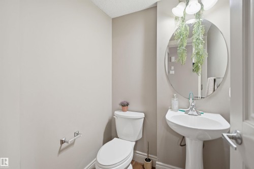 Pedestal sink with chrome fixtures and a circular mirror - 3533 11 Street, Edmonton, AB - Indoor Photo Showing Bathroom