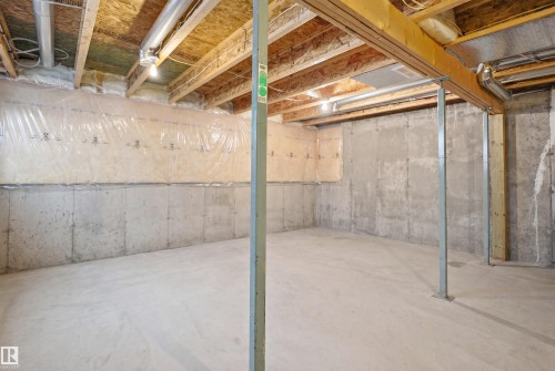 Unfinished basement featuring poured concrete walls and flooring, exposed wooden joists, and overhead lighting - 3533 11 Street, Edmonton, AB - Indoor Photo Showing Basement