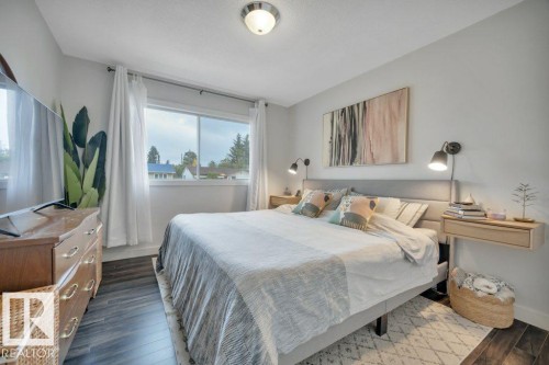 Bedroom featuring dark wood-finish flooring, light grey walls, and a recessed window with white curtains - 7715 73 Avenue, Edmonton, AB - Indoor Photo Showing Bedroom