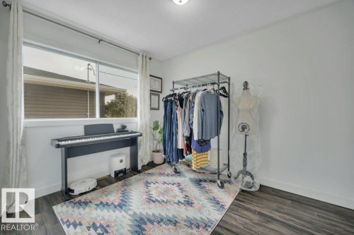 Light-filled room featuring a large window with white trim, wood-finish flooring, and light-colored walls - 7715 73 Avenue, Edmonton, AB - Indoor