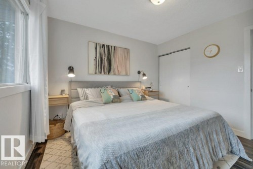 Bedroom featuring wood-finish flooring, a window with white trim, and a built-in closet with sliding doors - 7715 73 Avenue, Edmonton, AB - Indoor Photo Showing Bedroom