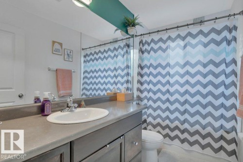 Bathroom vanity featuring an integrated oval sink, dark gray countertop, and coordinating cabinetry with chrome hardware - 7715 73 Avenue, Edmonton, AB - Indoor Photo Showing Bathroom
