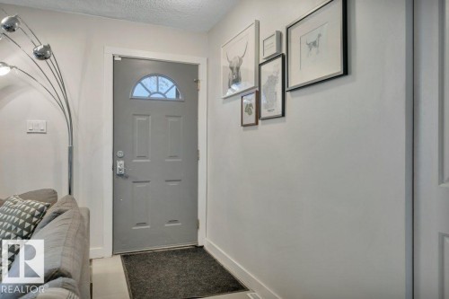 Entryway featuring a paneled door with an arched window, light-toned walls, and white trim - 7715 73 Avenue, Edmonton, AB - Indoor Photo Showing Other Room