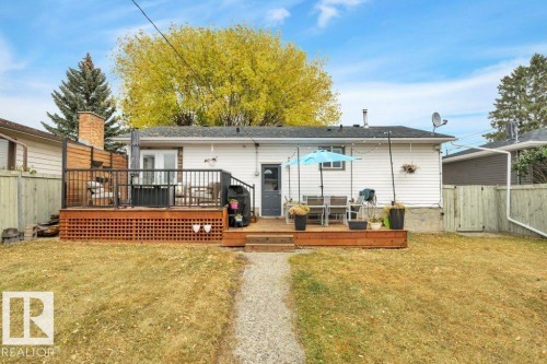 Expansive backyard featuring a gravel pathway, a large wood deck with black railings, and a privacy screen - 7715 73 Avenue, Edmonton, AB - Outdoor With Deck Patio Veranda