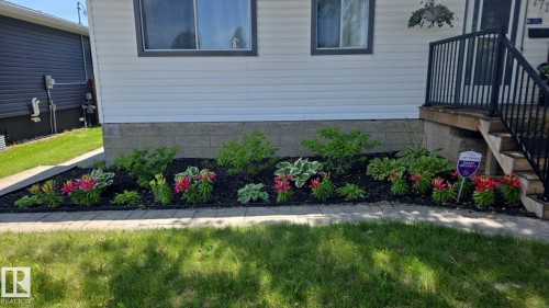 Front exterior featuring white siding, dark trim windows, and a raised foundation with block construction - 7715 73 Avenue, Edmonton, AB - Outdoor