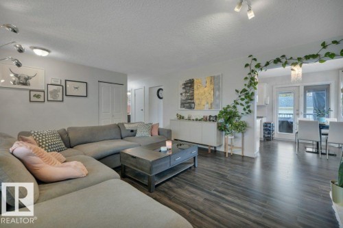 Spacious living area featuring wood-look flooring, recessed lighting, and a contemporary track light fixture - 7715 73 Avenue, Edmonton, AB - Indoor Photo Showing Living Room