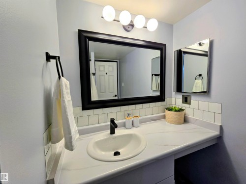 Bathroom vanity featuring an integrated sink, black matte faucet, and white countertop - 202 24 Alpine Place, St. Albert, AB - Indoor Photo Showing Bathroom