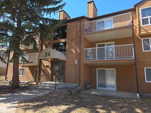 Multi-level building with wood-look siding, featuring multiple balconies with white railings and an arched entrance canopy - 202 24 Alpine Place, St. Albert, AB - Outdoor With Exterior