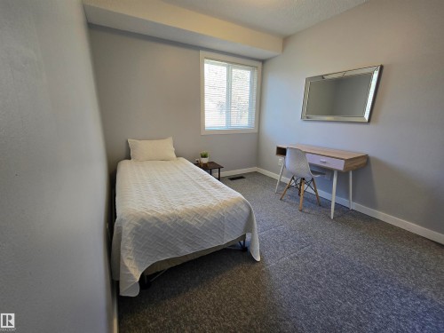 Light gray wall paint, window with horizontal blinds, gray textured carpet flooring, and white baseboards - 202 24 Alpine Place, St. Albert, AB - Indoor Photo Showing Bedroom