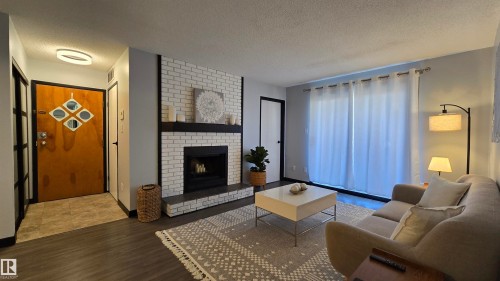 Living area featuring a white painted brick fireplace with a dark mantel, wood-finish flooring, and a sliding glass door - 202 24 Alpine Place, St. Albert, AB - Indoor Photo Showing Living Room With Fireplace