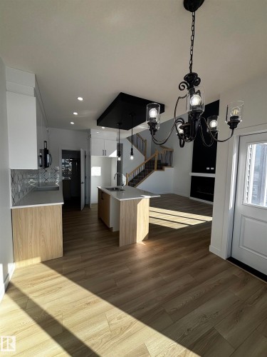 This property features an open-concept layout with light-toned flooring throughout, a kitchen island with a sink, and pendant lighting - 2012 210 St, Edmonton, AB - Indoor