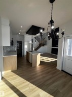 This property features an open-concept layout with light-toned flooring throughout, a kitchen island with a sink, and pendant lighting - 