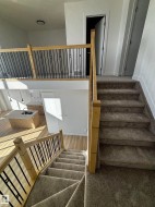 Staircases featuring light wood railings with black balusters, and carpeted steps - 