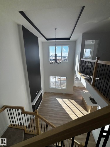 The main living area boasts high ceilings with decorative trim, large windows providing expansive views, and light-toned flooring - 2012 210 St, Edmonton, AB - Indoor Photo Showing Other Room