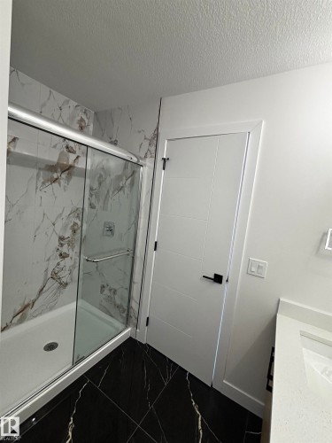 This bathroom features a contemporary shower with a glass enclosure and marble-look wall tiling - 2012 210 St, Edmonton, AB - Indoor