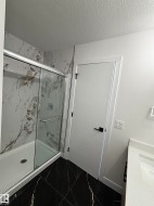 This bathroom features a contemporary shower with a glass enclosure and marble-look wall tiling - 