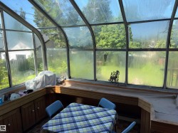 Sunroom featuring a curved glass roof, full-height windows, a built-in wooden countertop, integrated cabinetry, and brick-patterned tile flooring - 