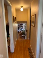 Hardwood flooring extends throughout this hallway with a traditional flush mount light fixture - 