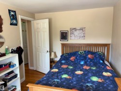 Hardwood flooring extends throughout this room, featuring light-colored walls and white trim - 