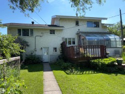 Rear exterior featuring a sunroom addition, wood deck, and stucco siding - 