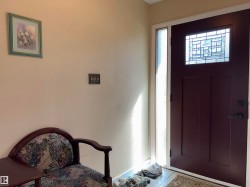 Entryway featuring a rich brown door with an intricate leaded glass insert, complemented by a frosted glass sidelight - 