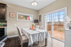 Sliding glass doors opening to an outdoor deck, dark wood-finish flooring, a built-in kitchen cabinet with a granite countertop, mosaic tile backsplash, and a horizontal transom window - 